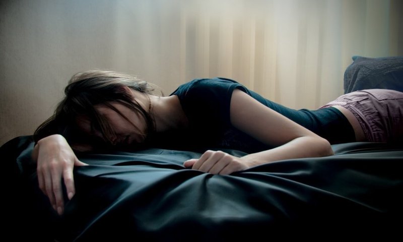 Грустная девушка лежит на кровати
